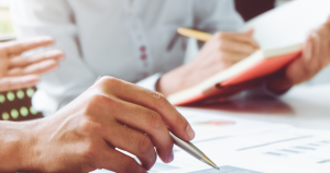 Two people sitting at a table reviewing charts and taking notes